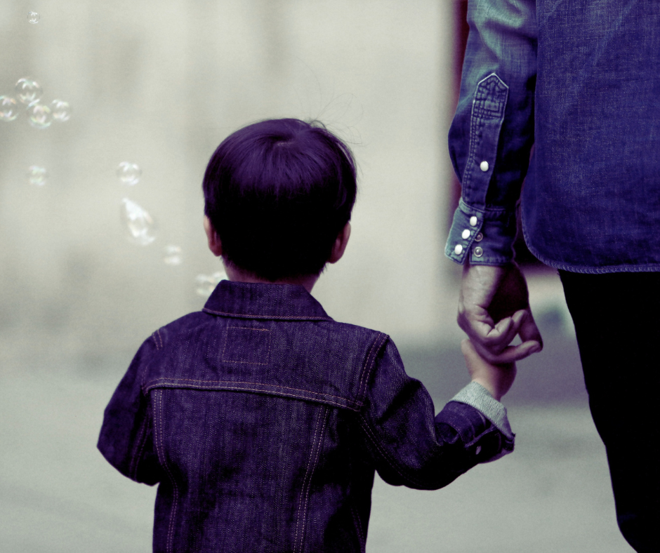 A little boy holds his mother's hand as she parents through generational trauma